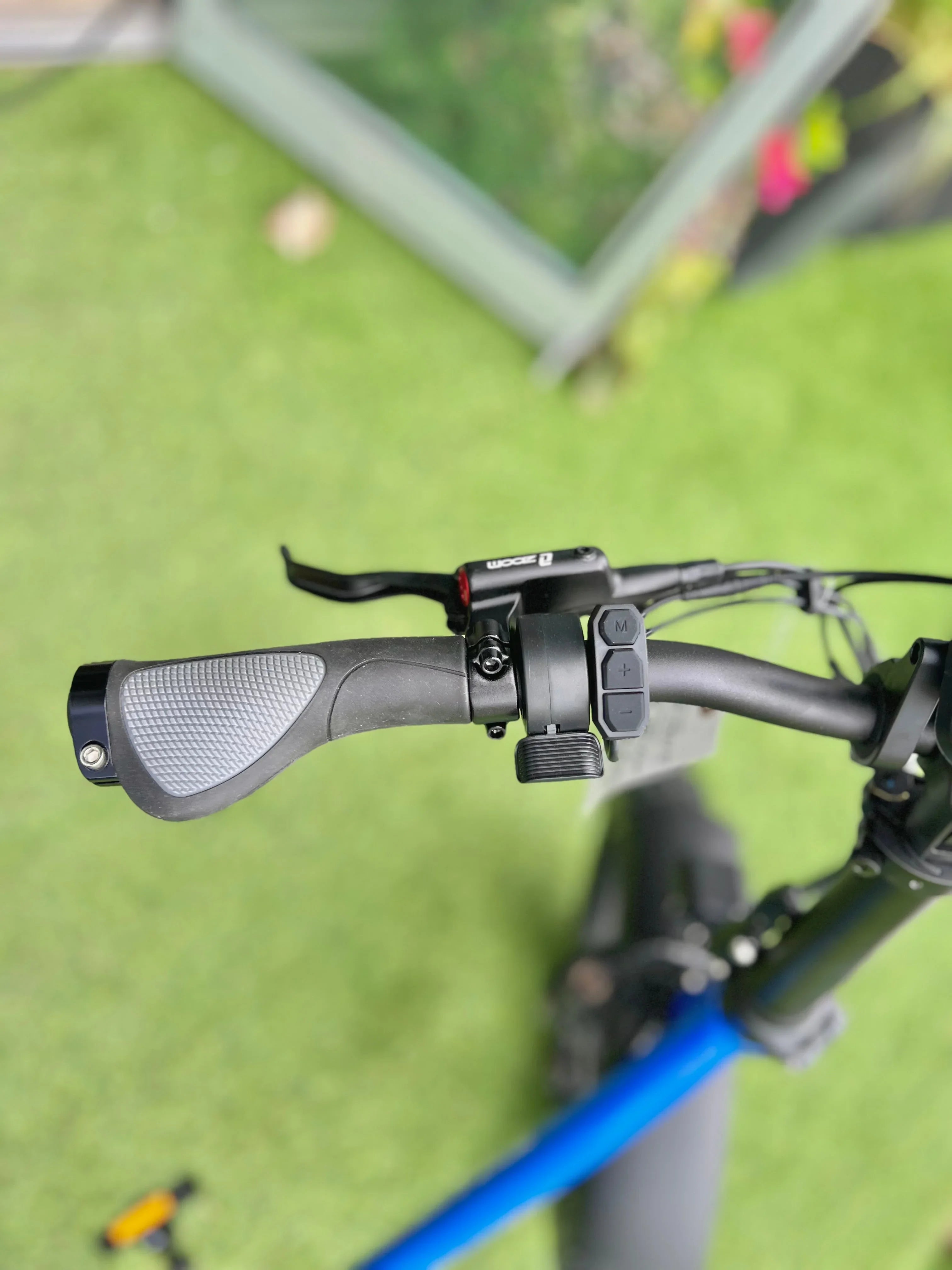 Electric bicycle handlebar with ergonomic grip, control buttons, and Zoom brake lever on grass