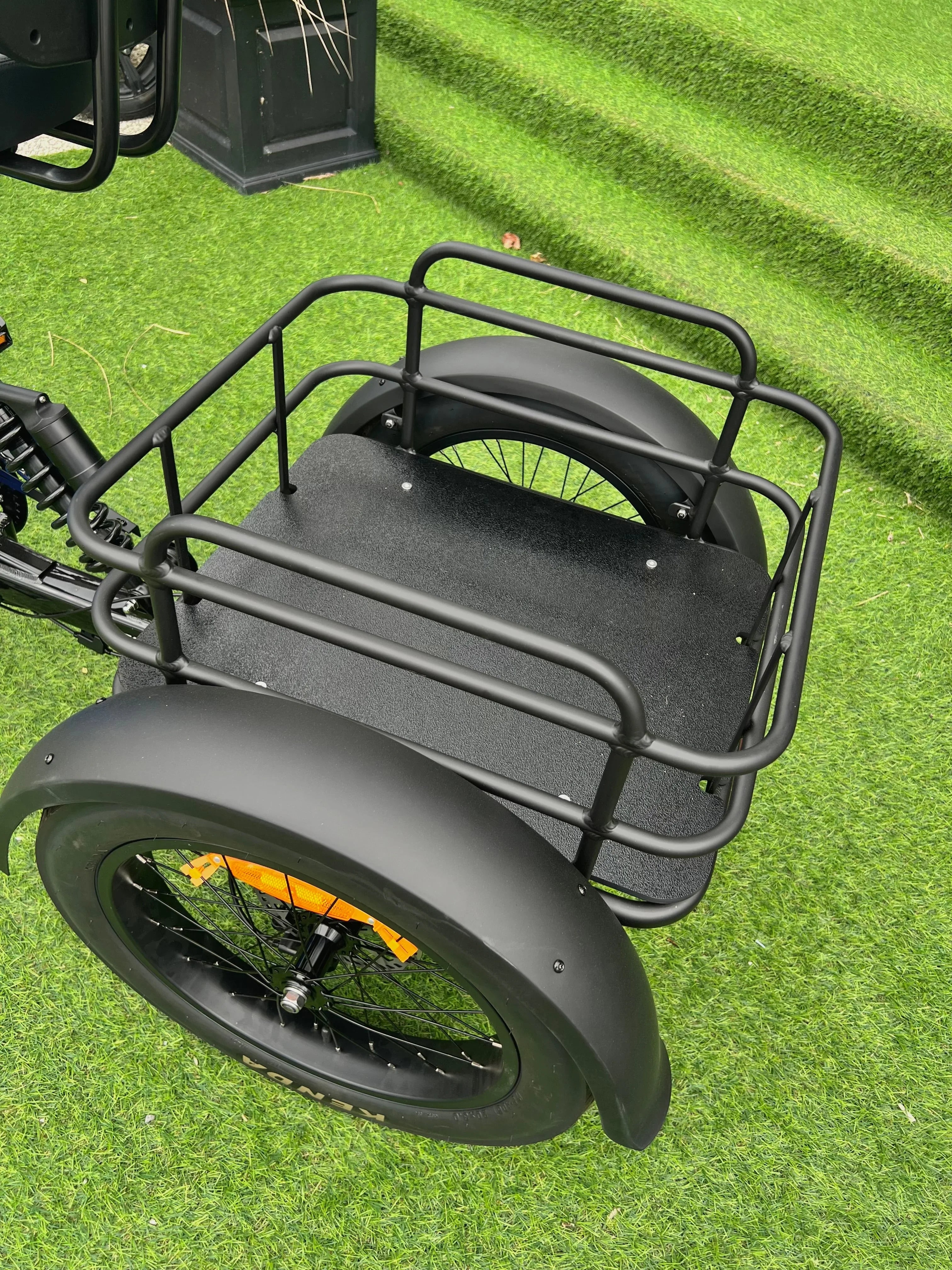 Black cargo bike rear basket with fat tire on artificial grass steps