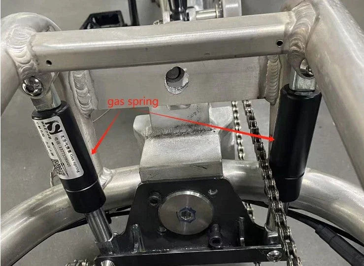 Close-up of a pivot gas spring installed on a metal frame with chain drive mechanism.