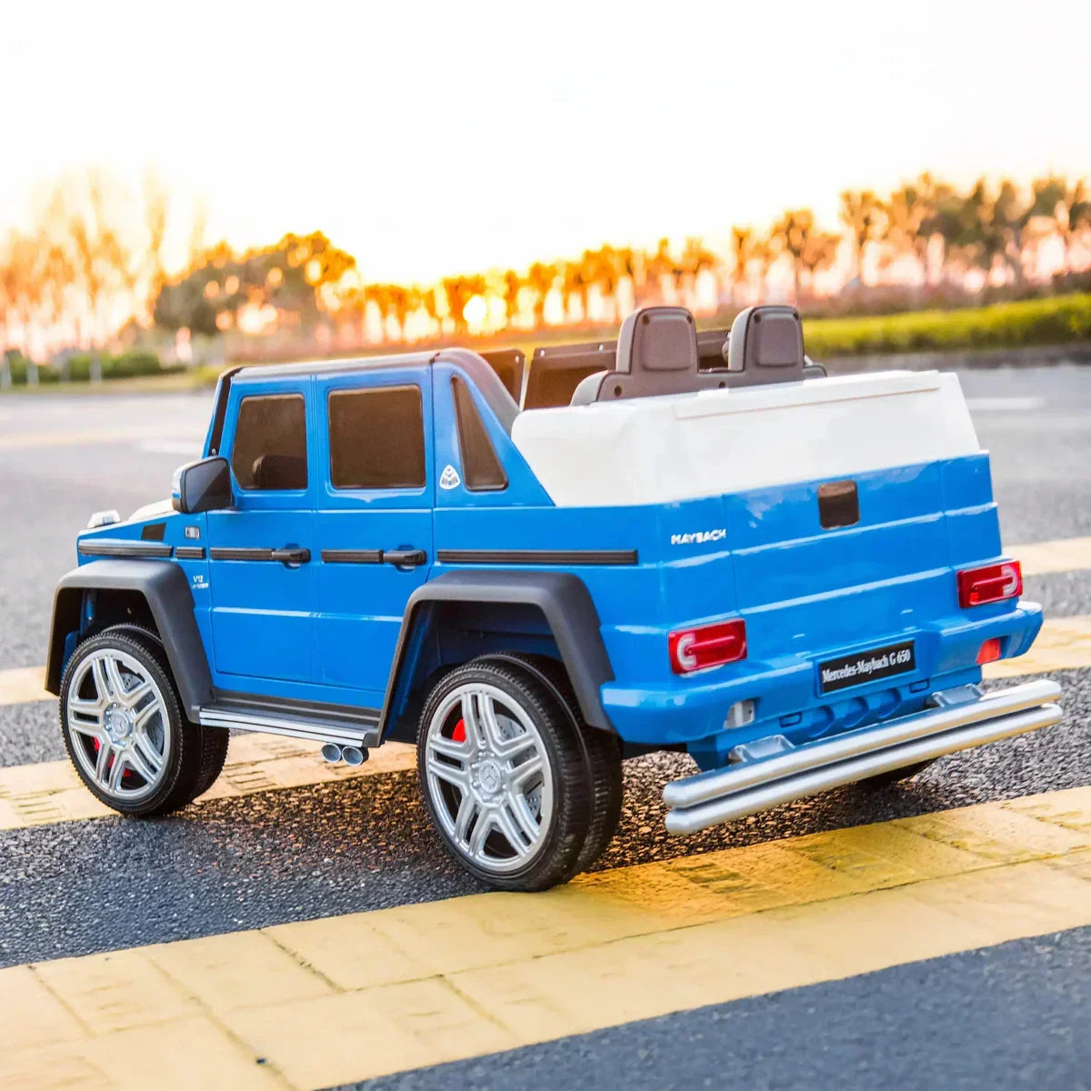 Blue Mercedes-Maybach G650 kids ride-on car on road with sunset background
