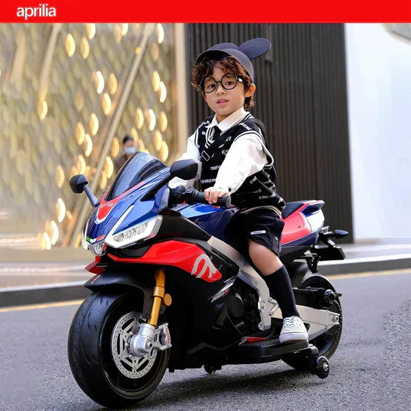 Young boy riding blue Aprilia kids motorcycle outdoors, wearing glasses and black vest.