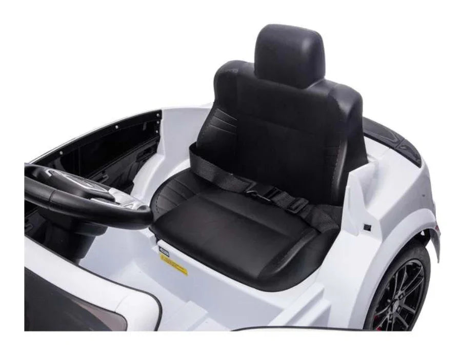 Black seat with seatbelt in a white kids electric ride on car, steering wheel visible