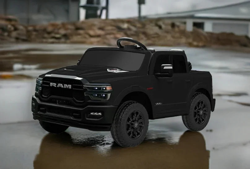 Black RAM kids ride-on toy truck parked on wet pavement outdoors