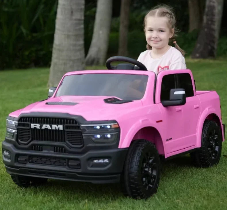 Smiling child driving pink RAM toy truck outdoors on green grass
