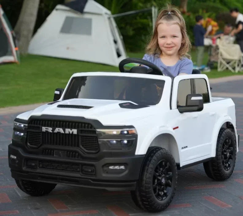 Smiling child drives white RAM toy truck outdoors near tents at a campsite