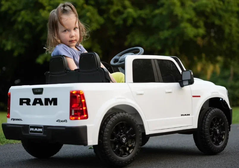 Child riding white toy RAM truck outdoors on pavement