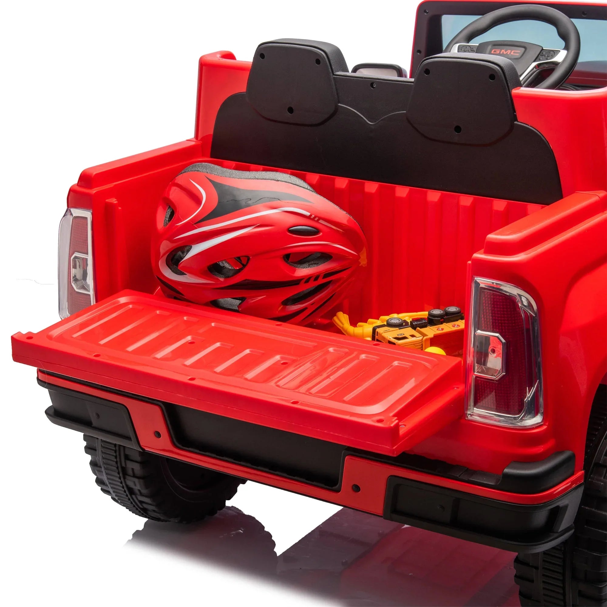 Red toy GMC truck bed with a red bike helmet and toy construction vehicles