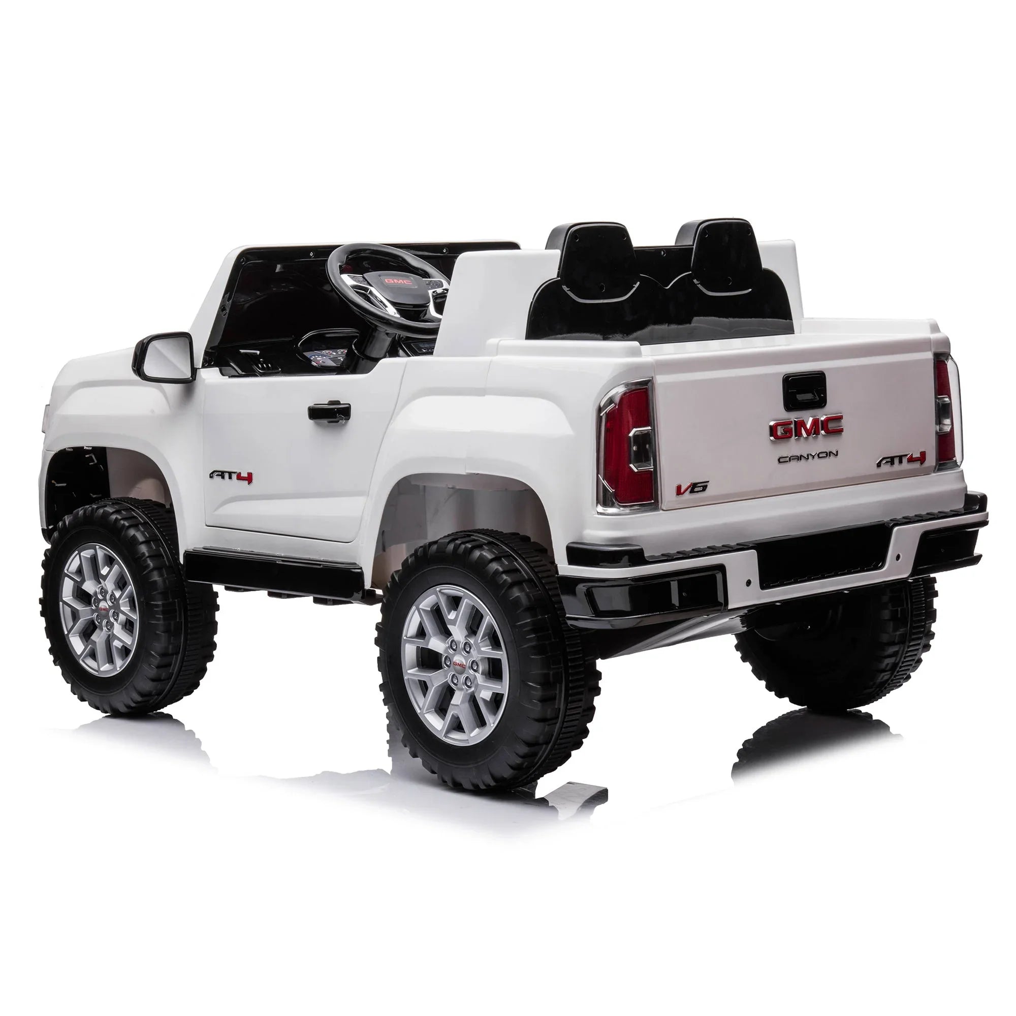 White GMC Canyon AT4 kids ride-on toy truck with black seats and silver wheels