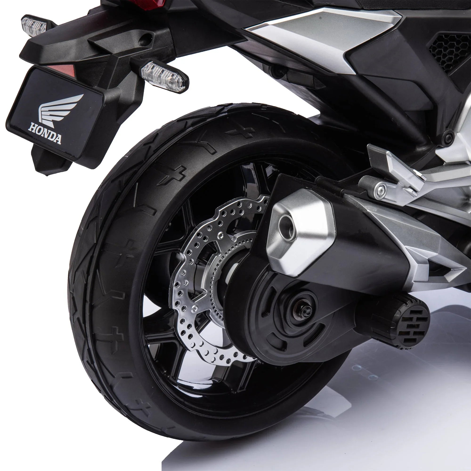 Close-up of Honda motorcycle rear wheel, disc brake, and exhaust system