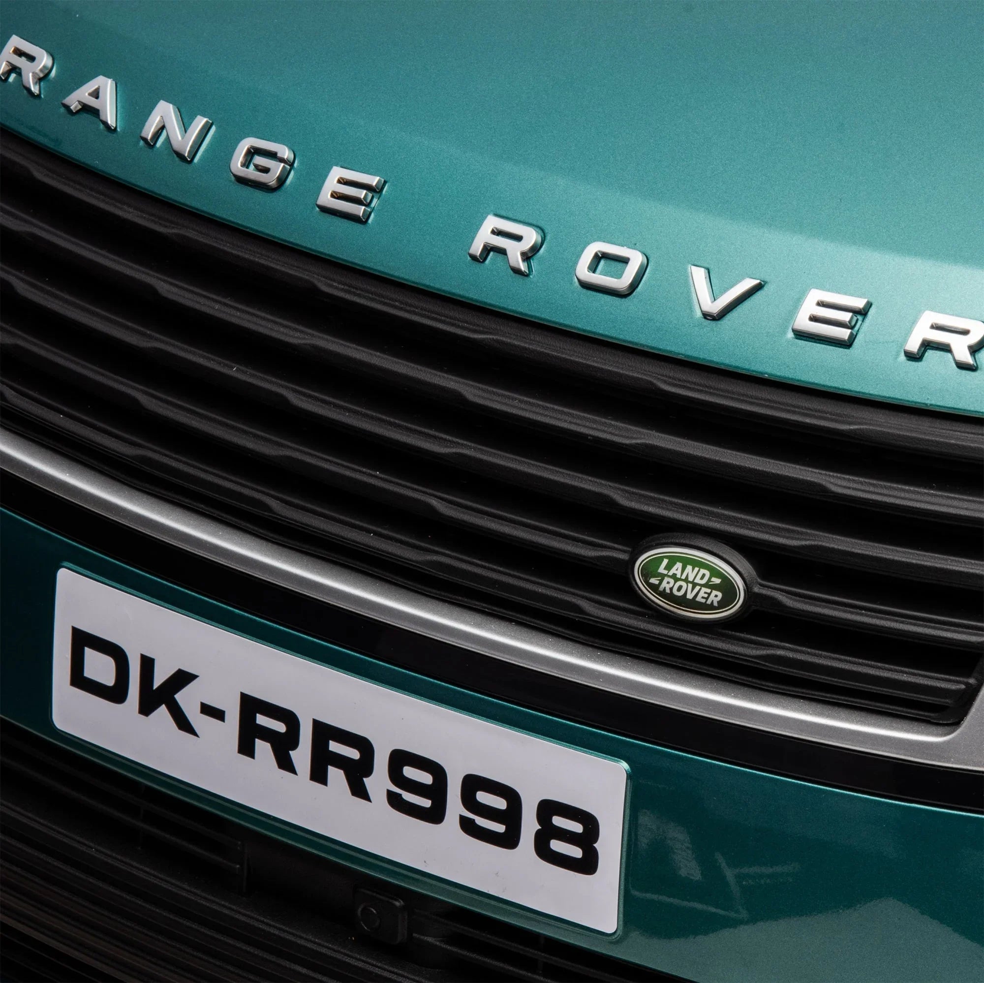 Close-up of green Land Rover front grille with LAND ROVER badge and DK-RR998 license plate