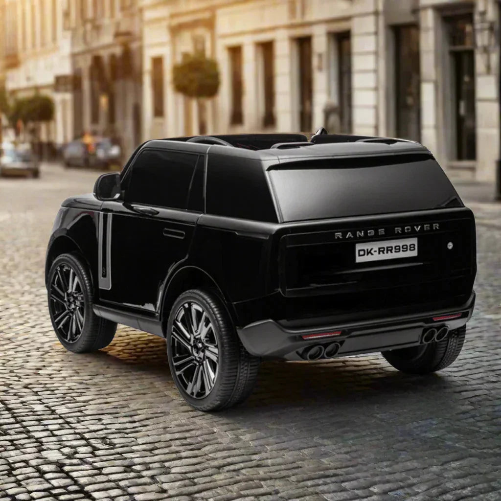 Black toy Range Rover ride-on car on cobblestone street, city background, luxury kids vehicle