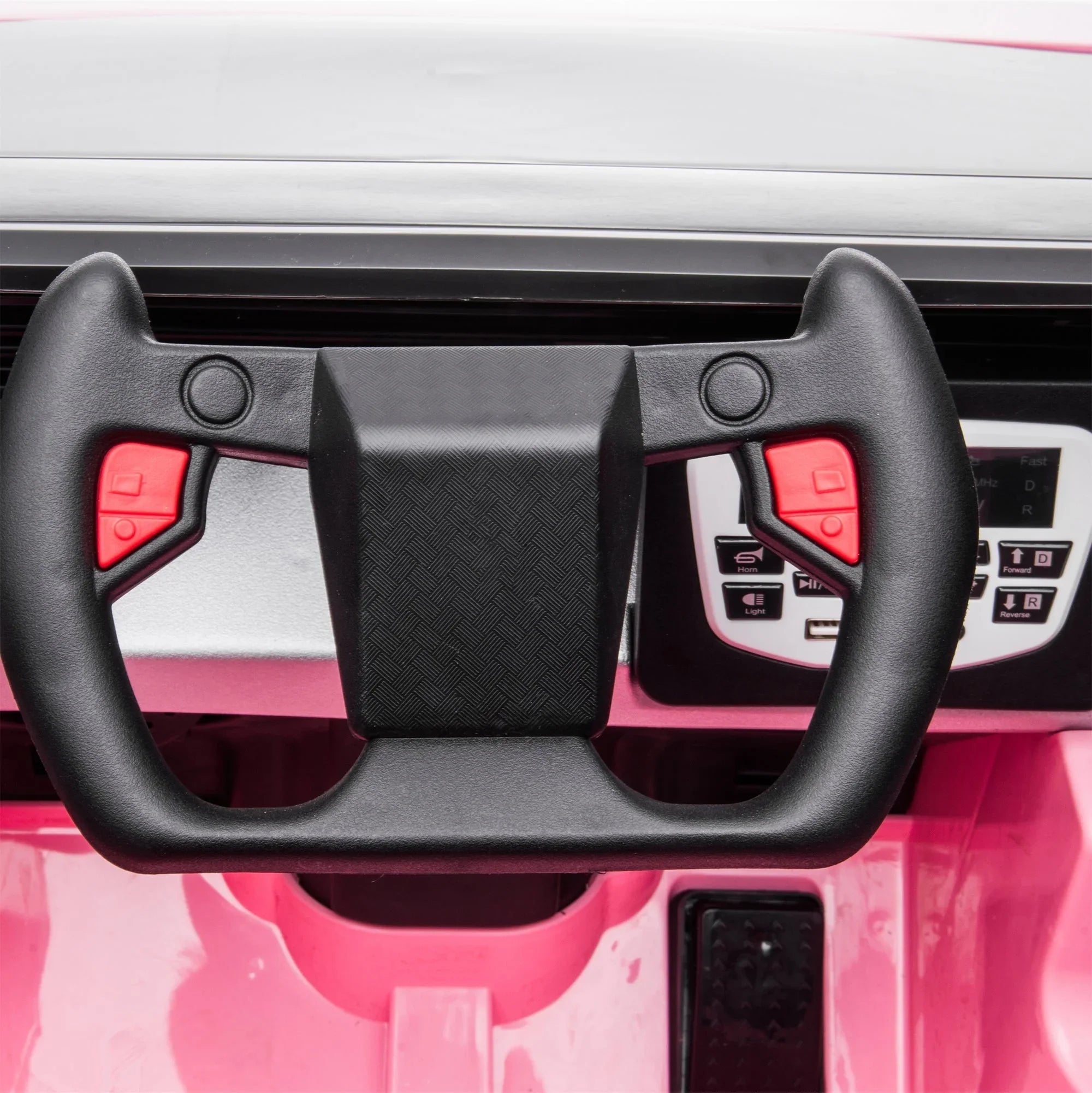 Close-up of black kid's car steering wheel on pink dashboard with control buttons