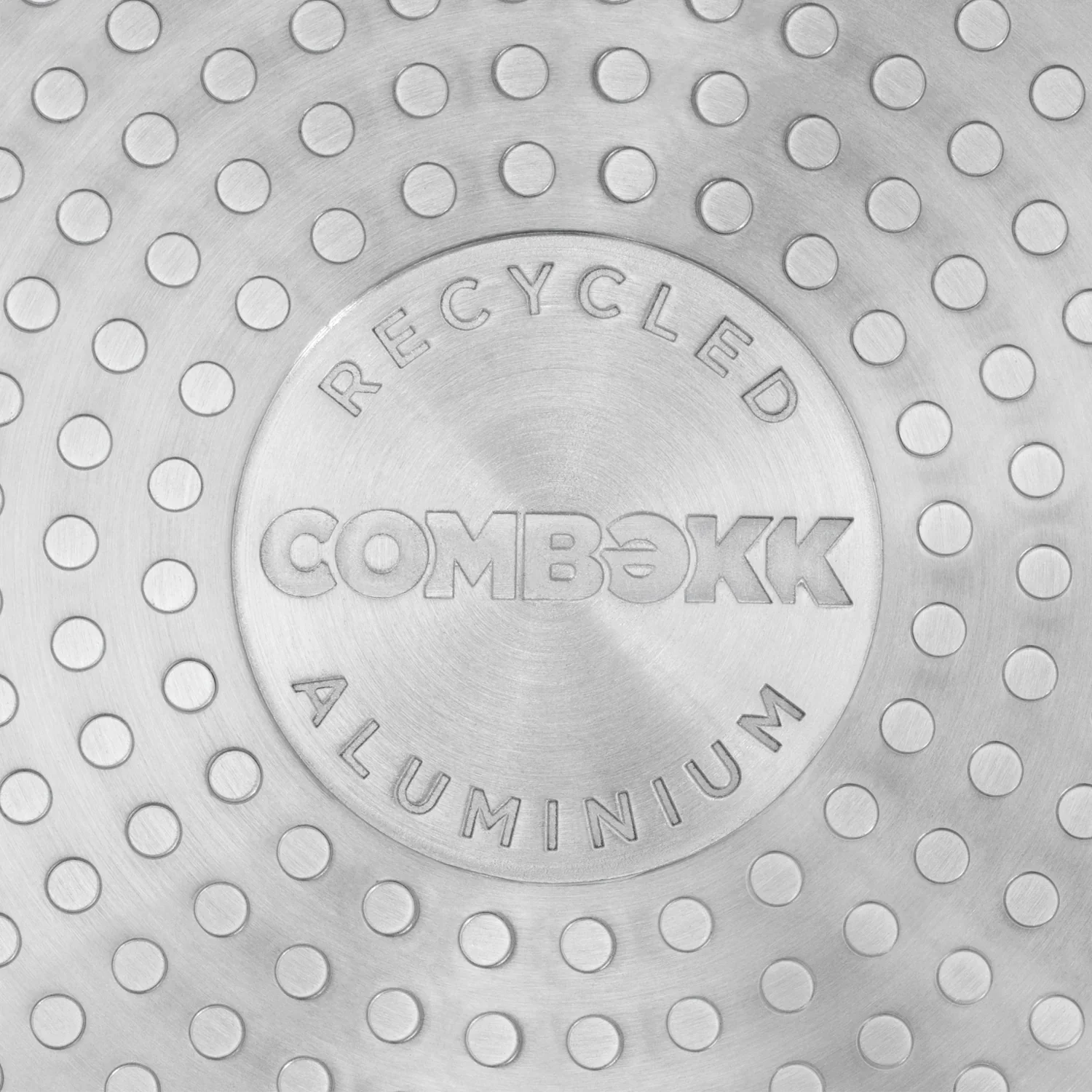 Close-up of COMBEKK recycled aluminium cookware base with textured, dotted metal pattern.