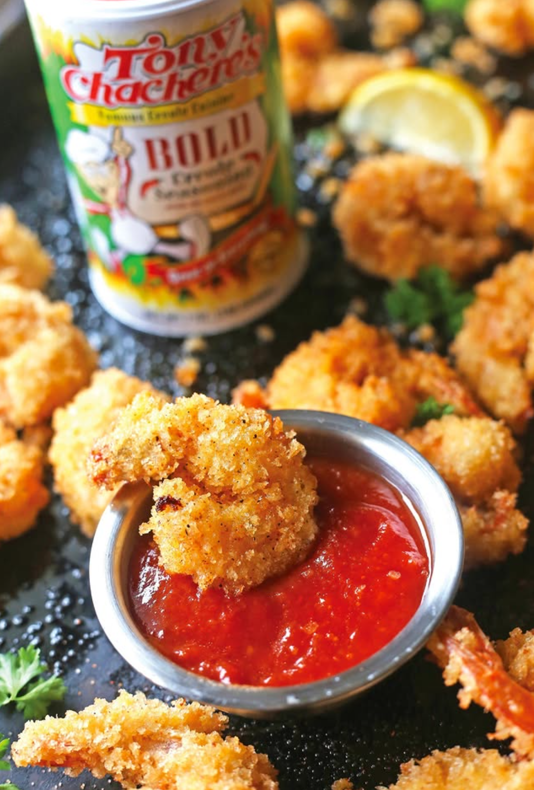 Fried shrimp with cocktail sauce and Creole seasoning on a black tray