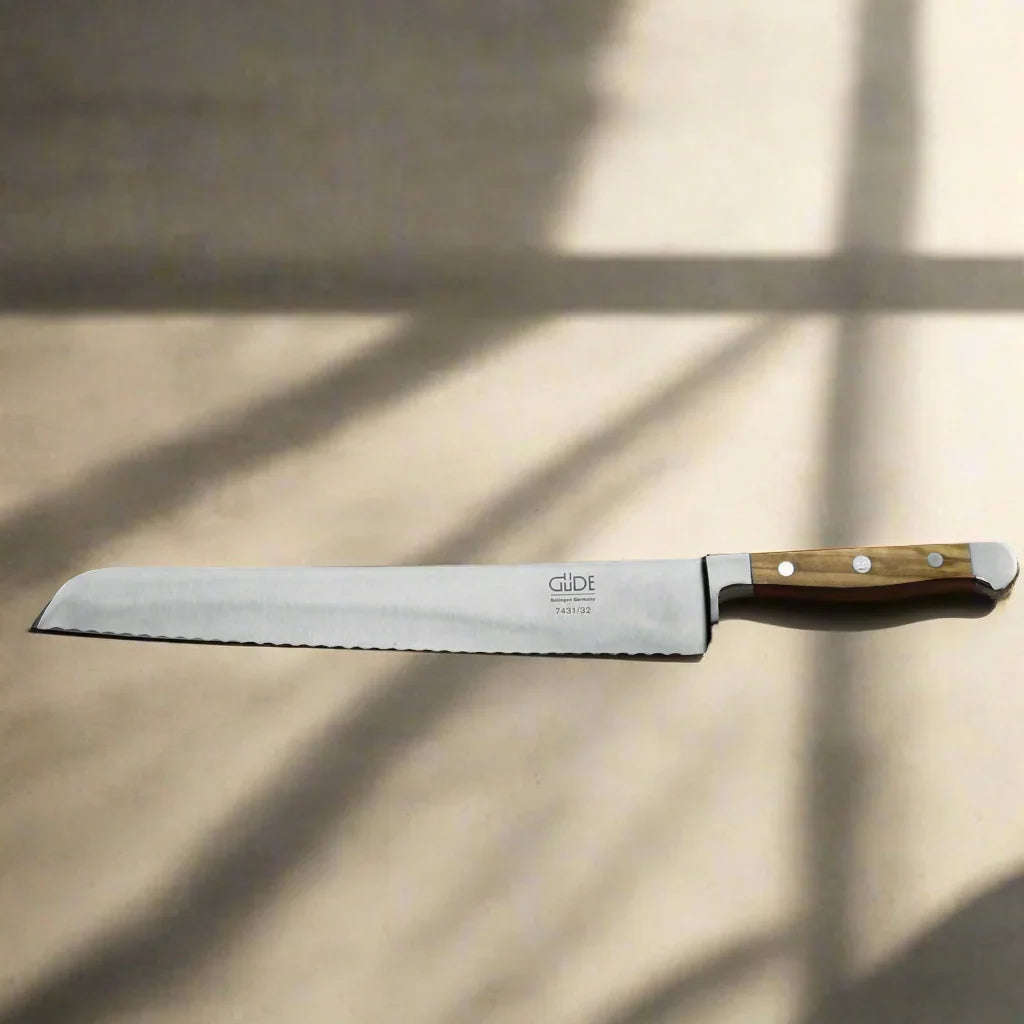 Serrated bread knife with wooden handle on tan surface, outdoor camping gear accessory