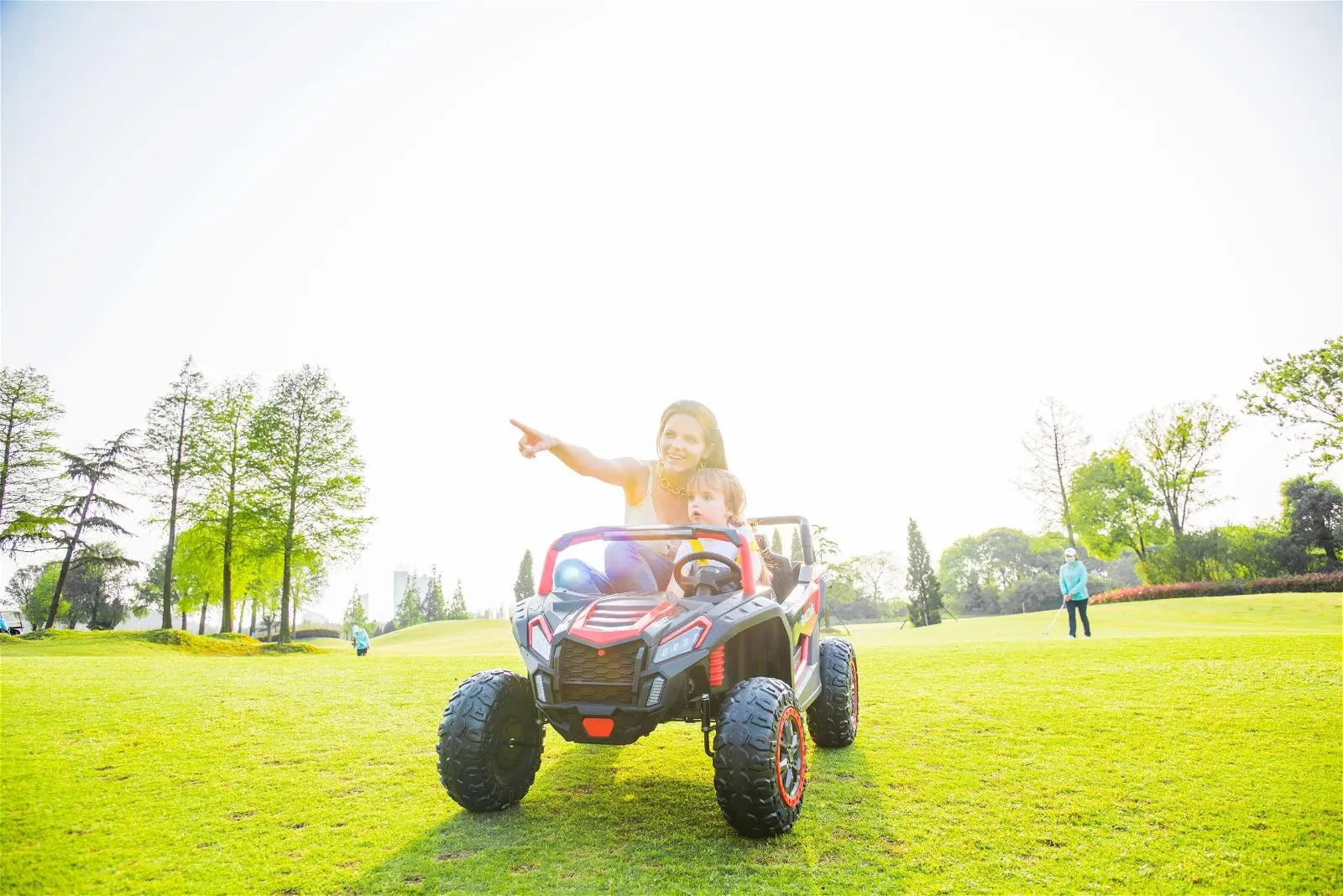 Electric 4x4 ride-on buggy with two seats, child and adult on grassy field, outdoor play