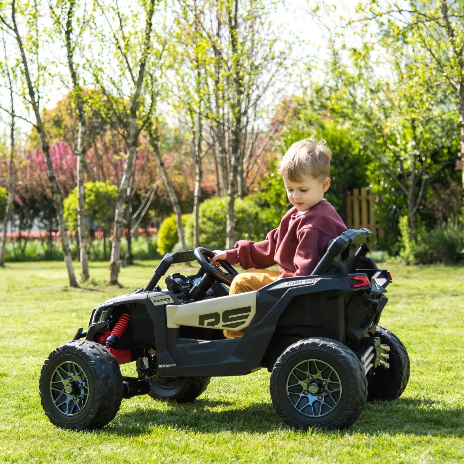 Child riding a 24V Can-Am Maverick kids electric UTV on grass in a park setting