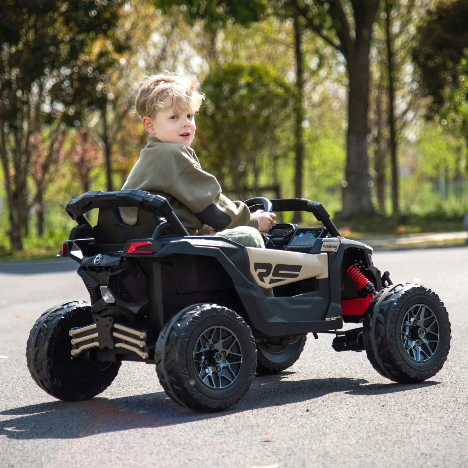 Child riding a 24V black and tan kids electric UTV toy outdoors on a paved path