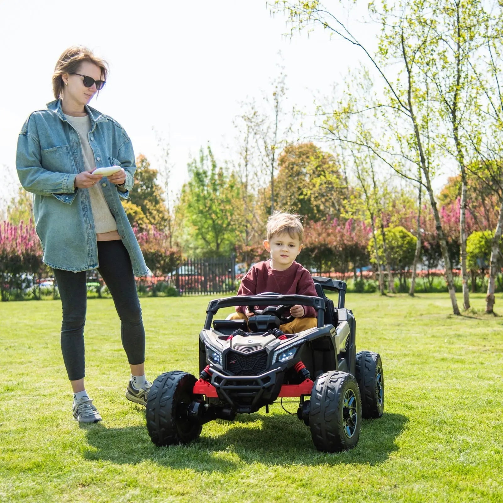 Child driving 24V kids electric ride-on UTV car outdoors with adult supervising