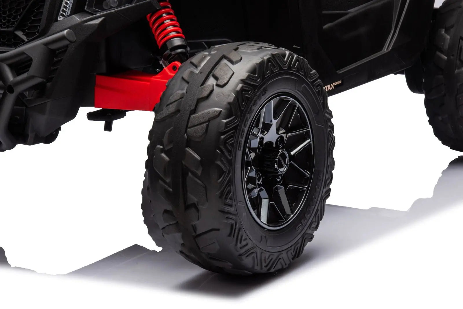 Close-up of rugged black tire and red suspension on kids electric ride-on UTV
