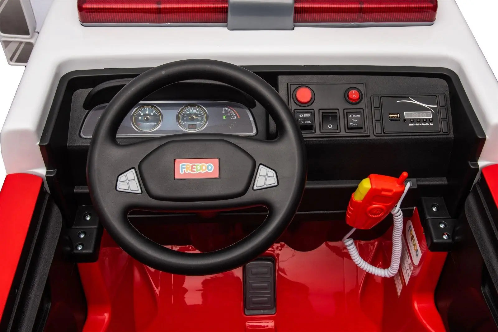 Closeup of kids' ride-on fire truck dashboard with steering wheel, controls, and toy radio