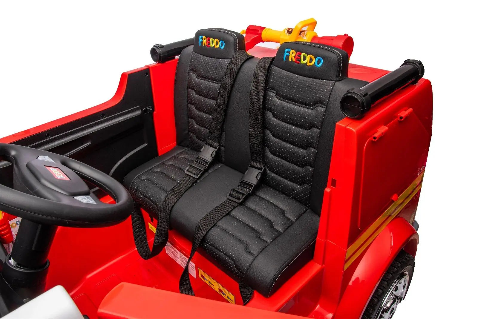 Close-up of a red 2-seater kids ride-on fire truck with seat belts and steering wheel