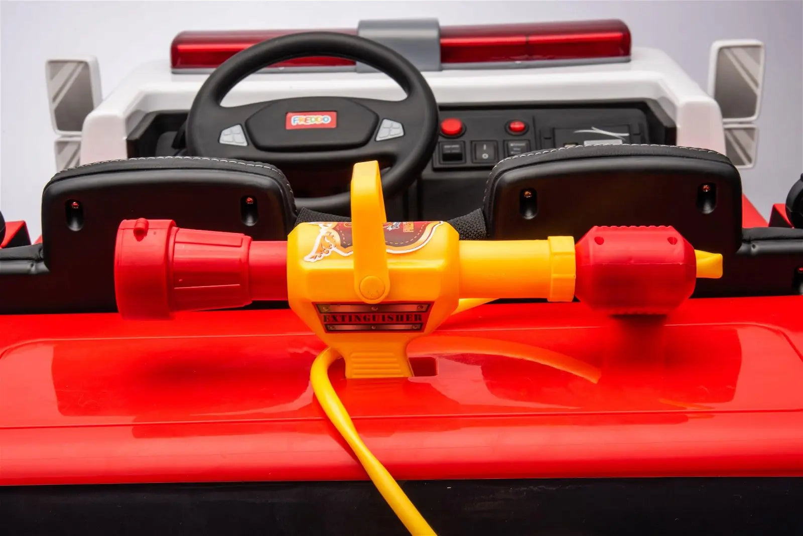 Close-up of toy fire truck dashboard with steering wheel and red-yellow toy extinguisher