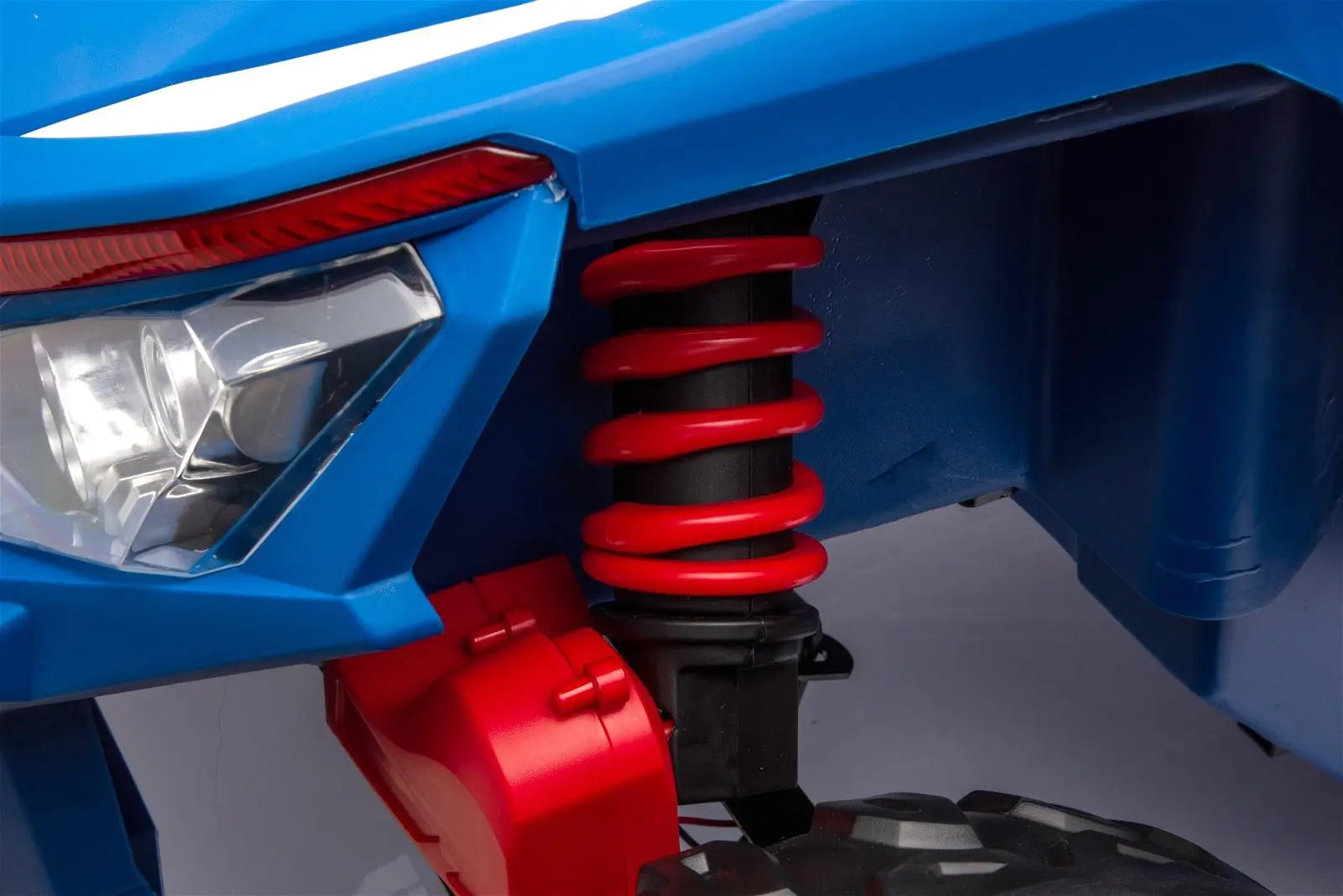 Close-up of kids ride-on UTV blue front headlight, red coil spring, rugged tire