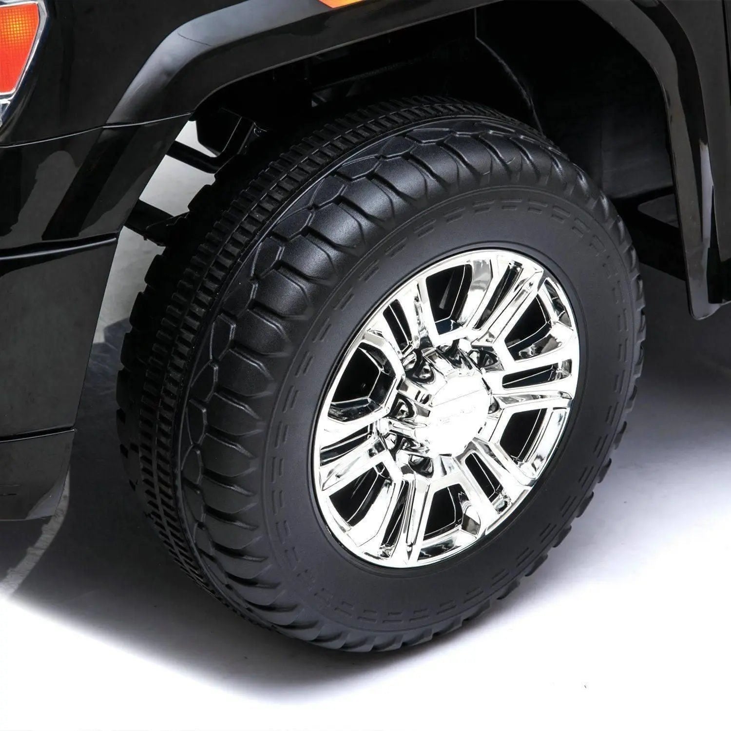 Close-up of ride-on car tire with rugged tread and shiny chrome wheel rim
