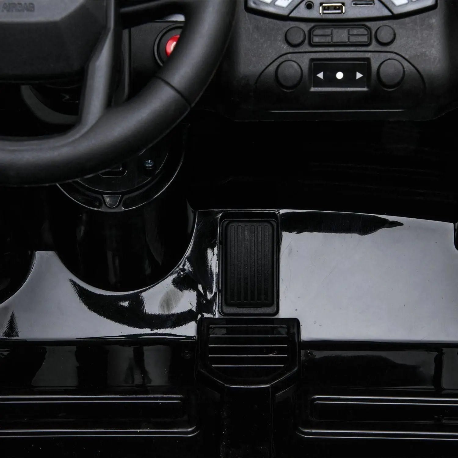 Kids ride on car dashboard and foot pedal close-up, black interior, steering wheel visible