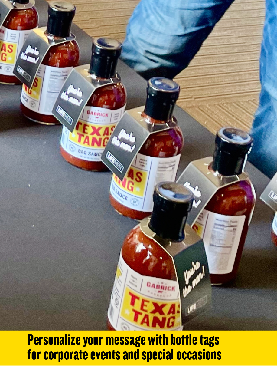 Texas Tang BBQ sauce bottles with personalized tags on a table, ideal for events and gifts