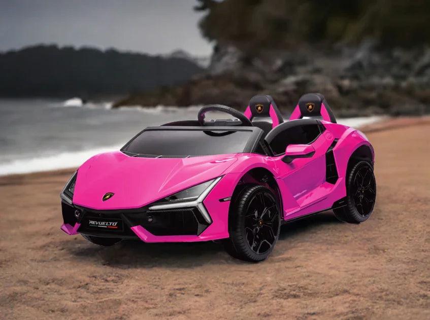 Pink toy Lamborghini car parked on sandy beach with ocean and trees in the background
