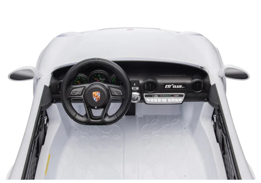 Toy Porsche dashboard with steering wheel, gauges, and interior details, white model