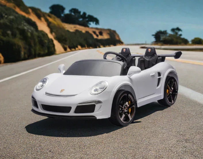 White kids electric Porsche ride-on car with black wheels on scenic winding road