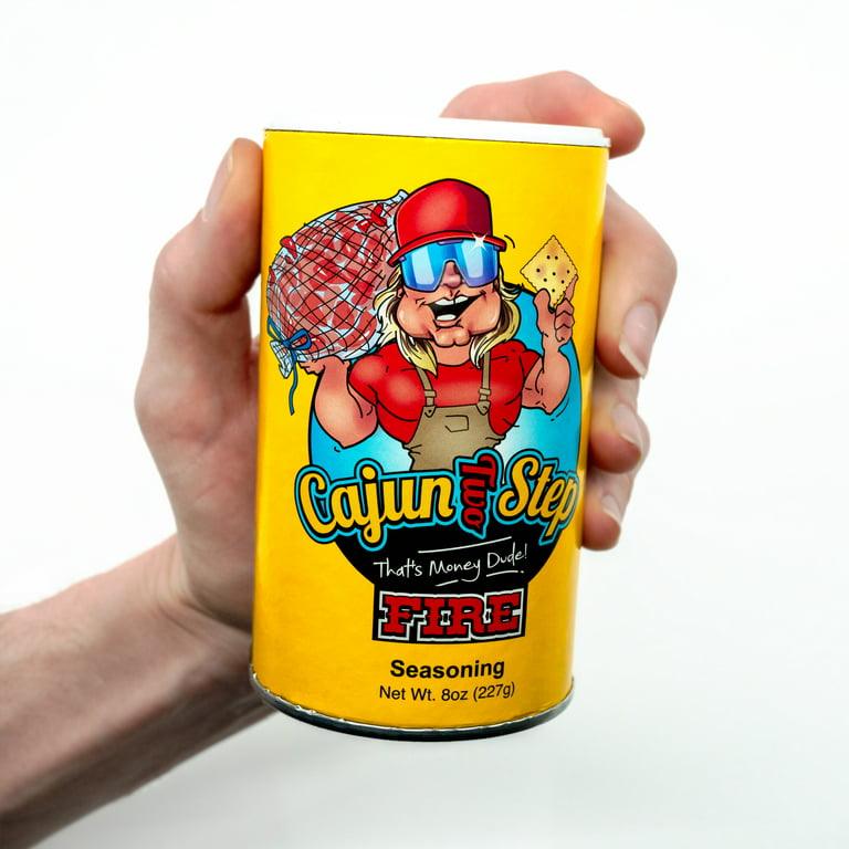 Hand holding Cajun Two Step Fire seasoning can, yellow label, cartoon chef logo, 8oz container