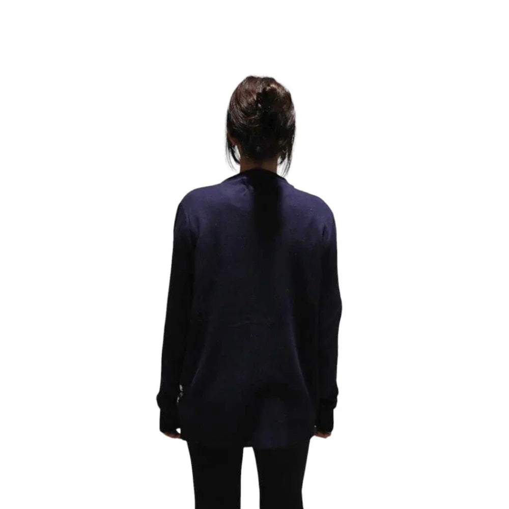 Woman in navy sweater and black leggings standing with back facing on white background