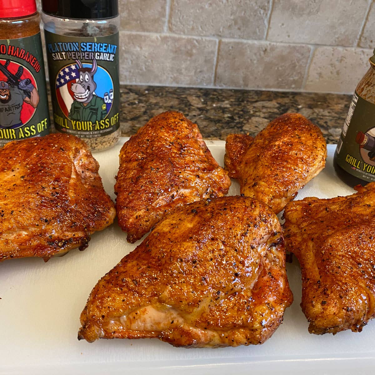 Grilled, seasoned chicken breasts on a cutting board with savory spice rubs nearby