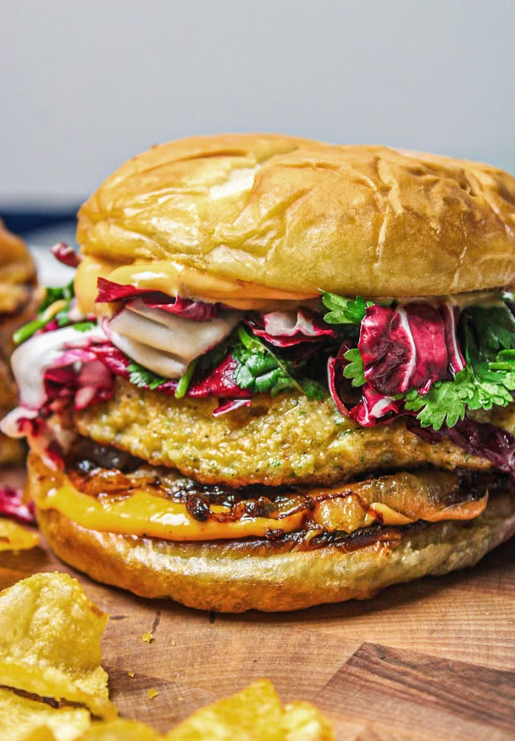 Close-up of a gourmet burger with cheddar, caramelized onions, fresh greens on a toasted bun