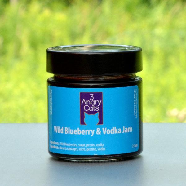 Jar of 3 Angry Cats Wild Blueberry & Vodka Jam on outdoor surface with green background