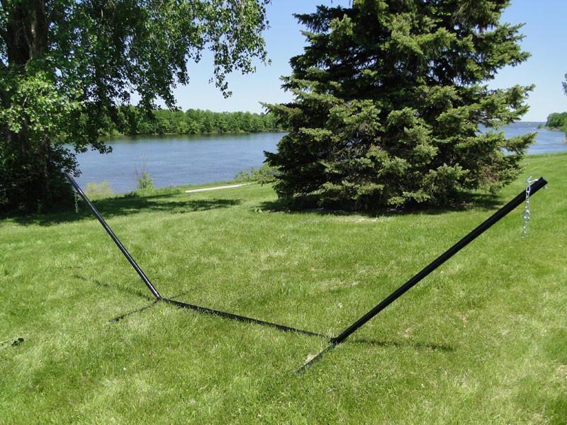 15-foot tri-beam hammock stand on green grass by a river with trees in background