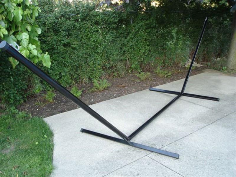 15-foot black tri-beam hammock stand on patio with greenery in background