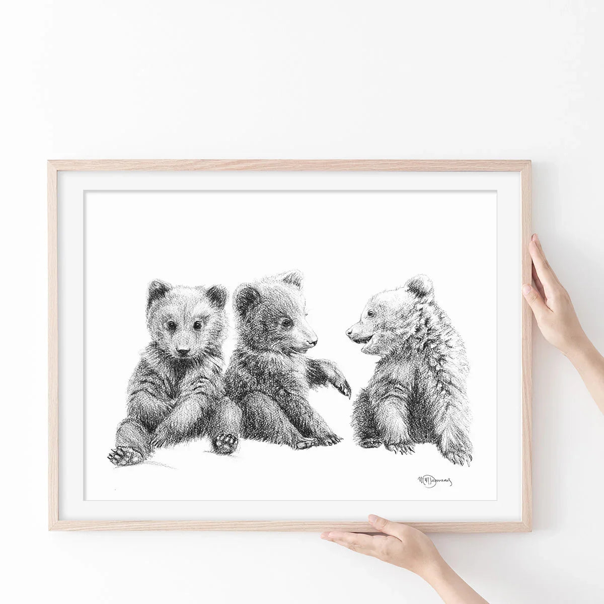 Hand holding framed sketch art of three baby bears sitting, black and white animal wall decor
