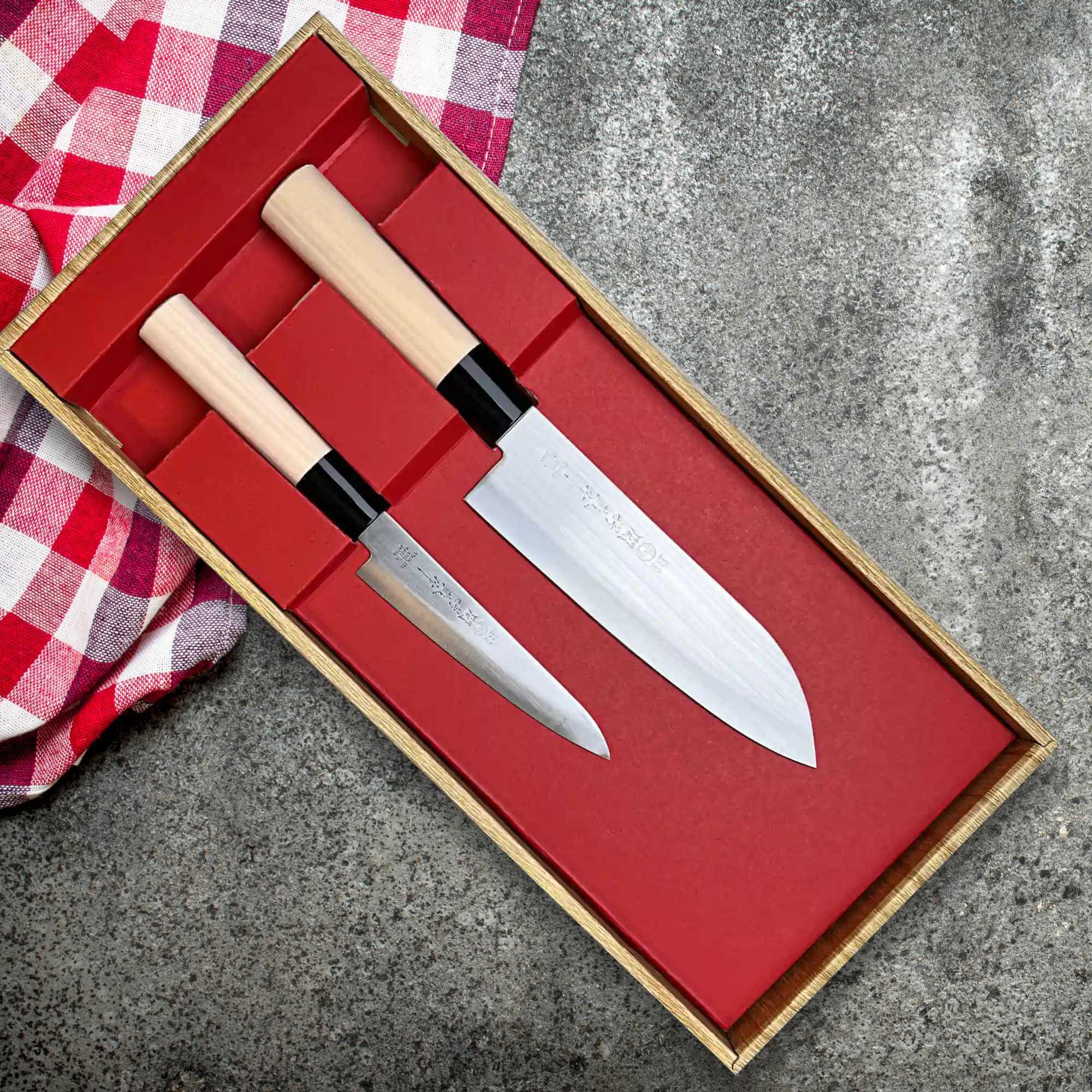 Set of two Japanese kitchen knives with wooden handles in a gift box on a stone surface