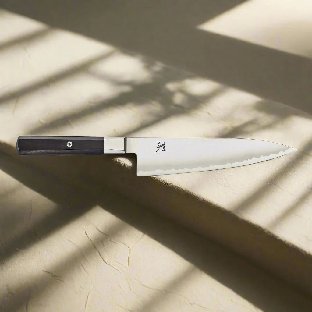 Japanese-style chef knife with wooden handle on textured surface in natural light