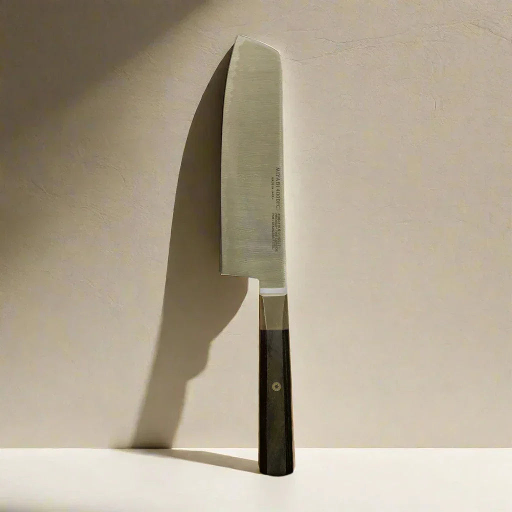 Japanese-style chef knife with wooden handle and stainless steel blade on beige background