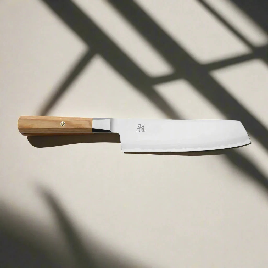 Japanese chef knife with wooden handle on a sunlit surface, kitchen gear