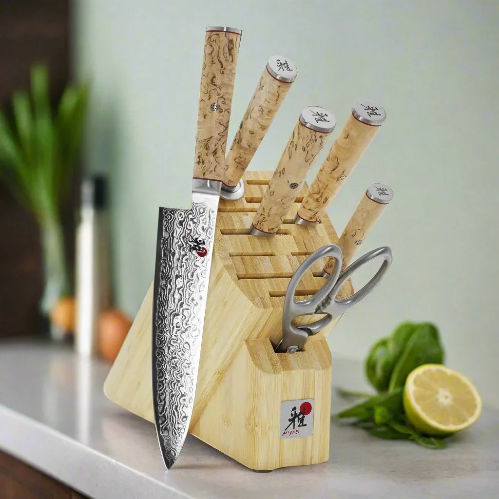 Damascus steel kitchen knife set with birch handles in bamboo block on countertop