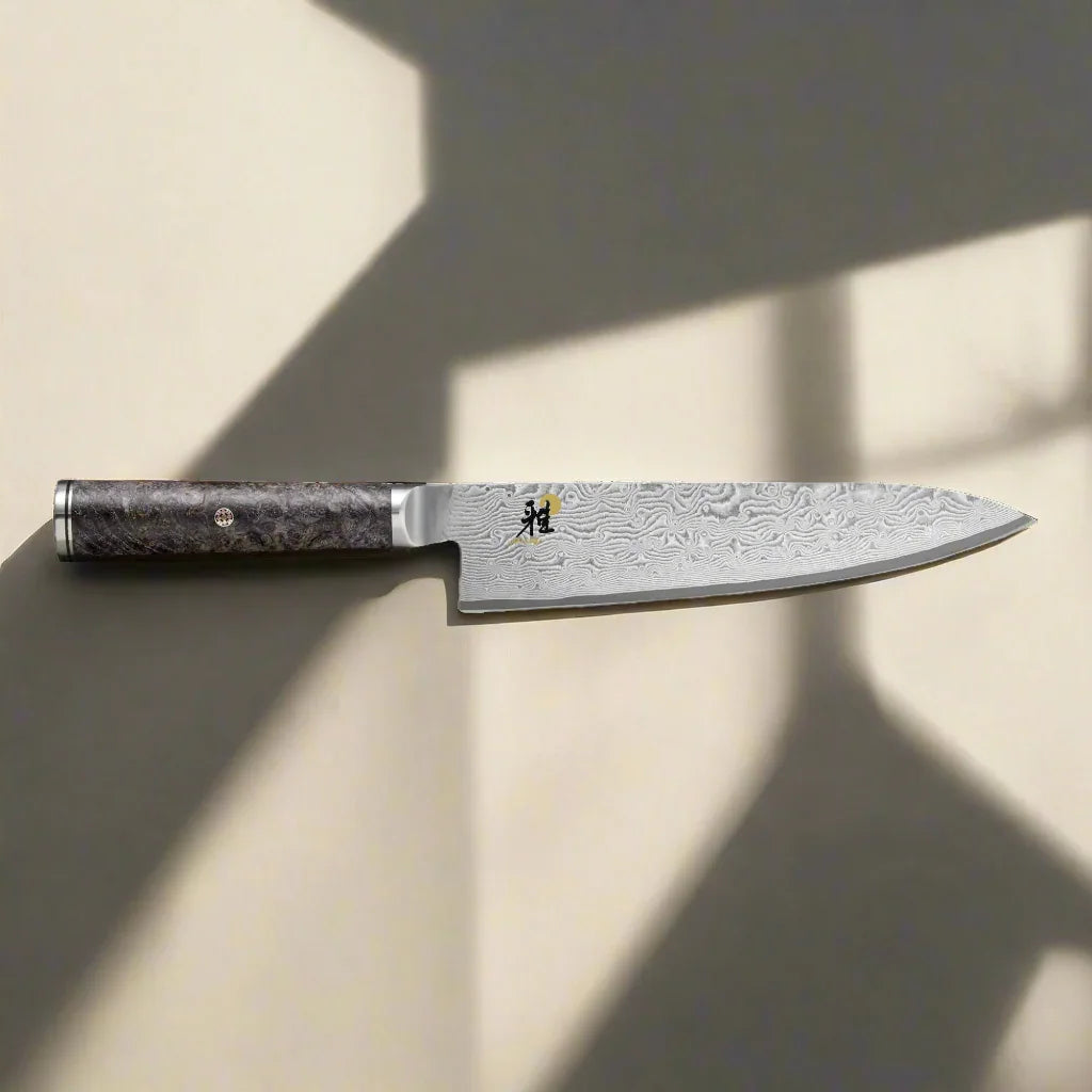 Damascus steel chef knife with dark wood handle on beige background, hunting and camping gear