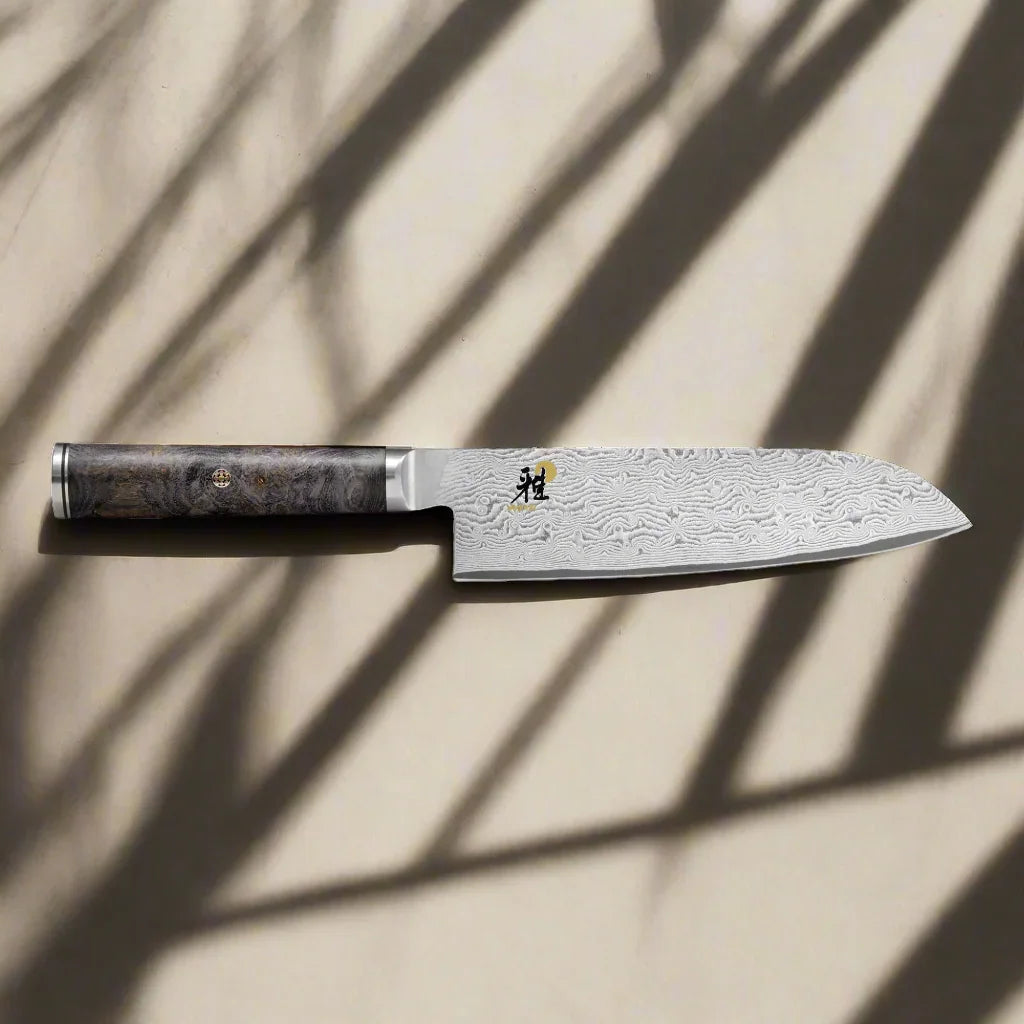 Damascus steel chef knife with patterned blade and dark wood handle on neutral background