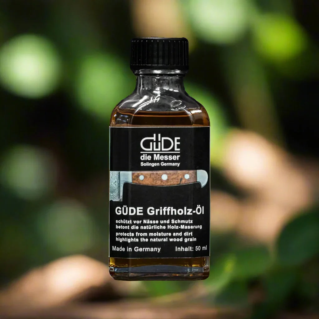 Güde Griffholz wood handle oil bottle for knives, 50ml, outdoors with foliage background
